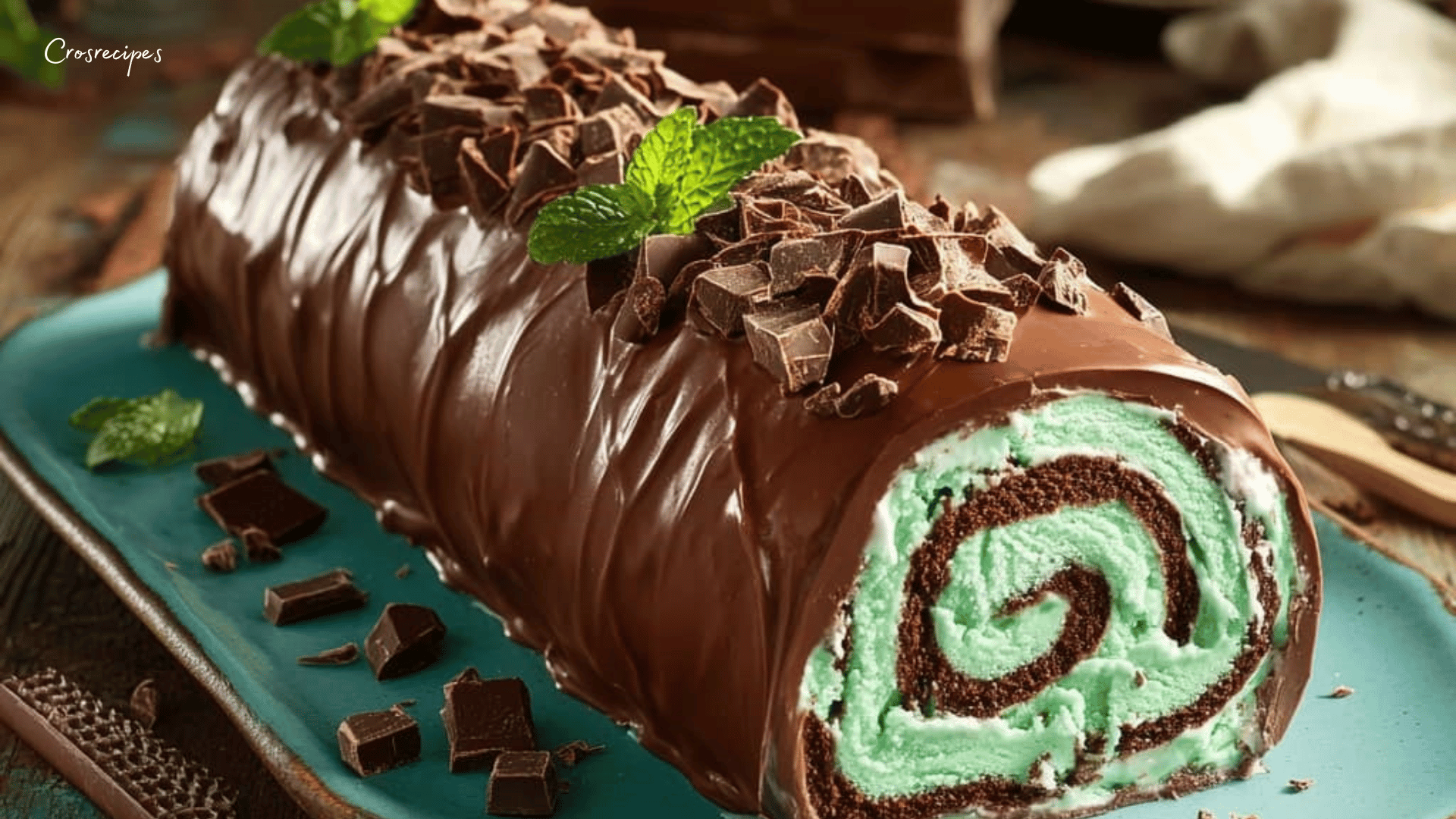 Bûche menthe chocolat glacée décorée de feuilles de menthe et de copeaux de chocolat noir.