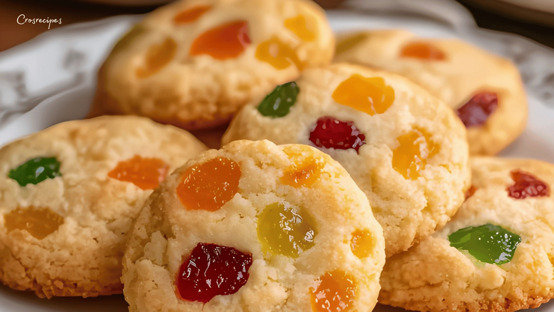 Biscuits aux fruits confits dorés, servis sur une assiette avec une tasse de thé.