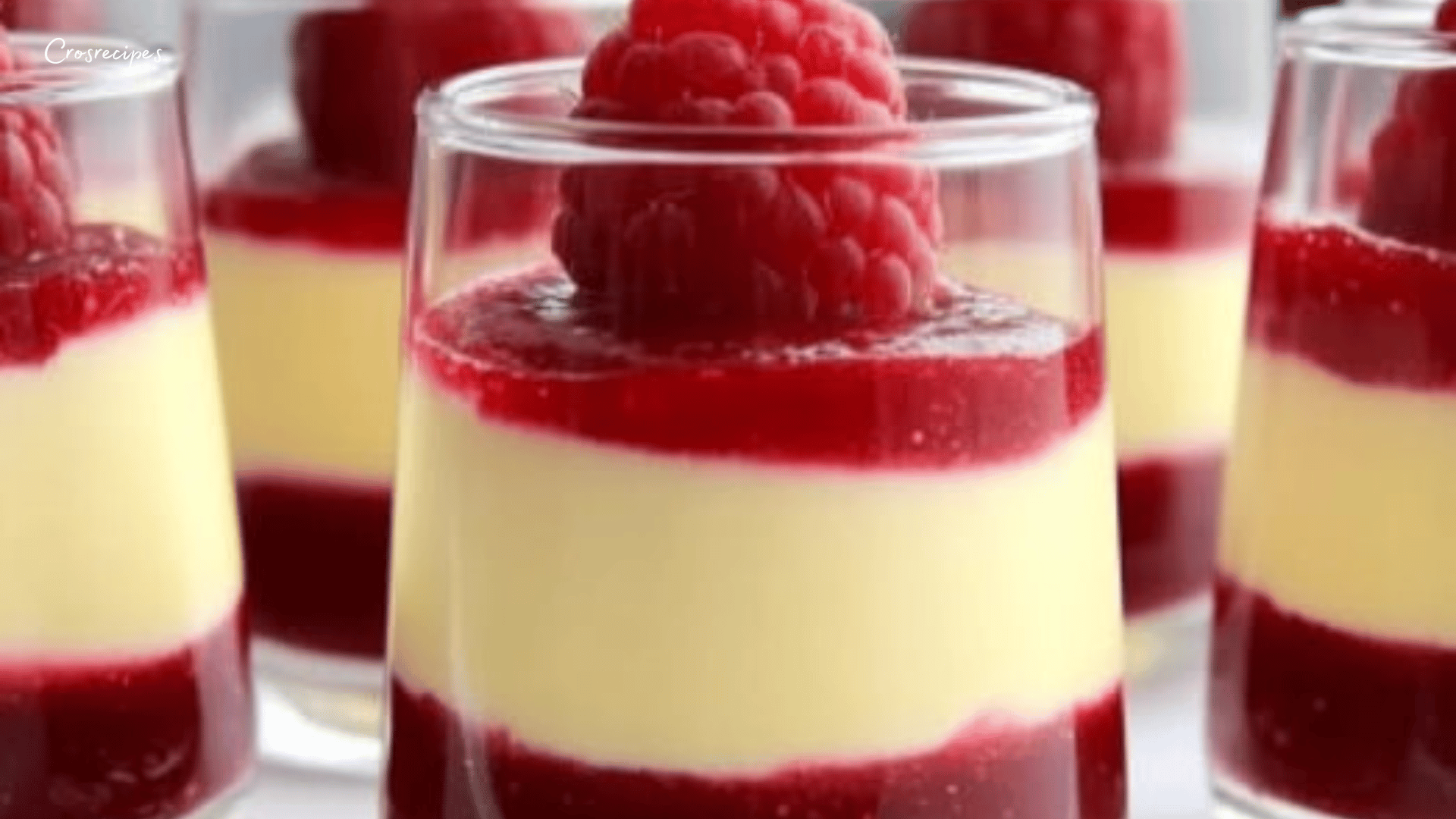 Verrines élégantes de mousse au chocolat blanc et à la framboise, décorées de framboises fraîches et de feuilles de menthe.