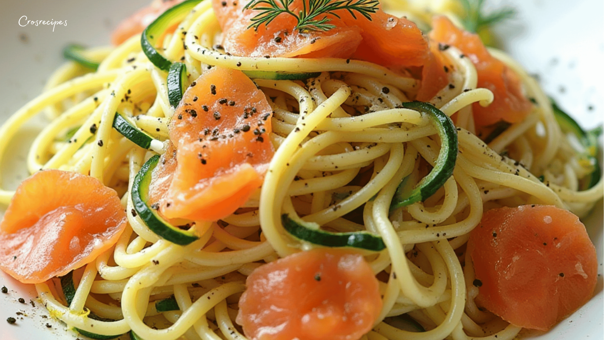 Assiette de spaghetti au saumon fumé et courgettes, parsemée de persil et de zestes de citron frais.