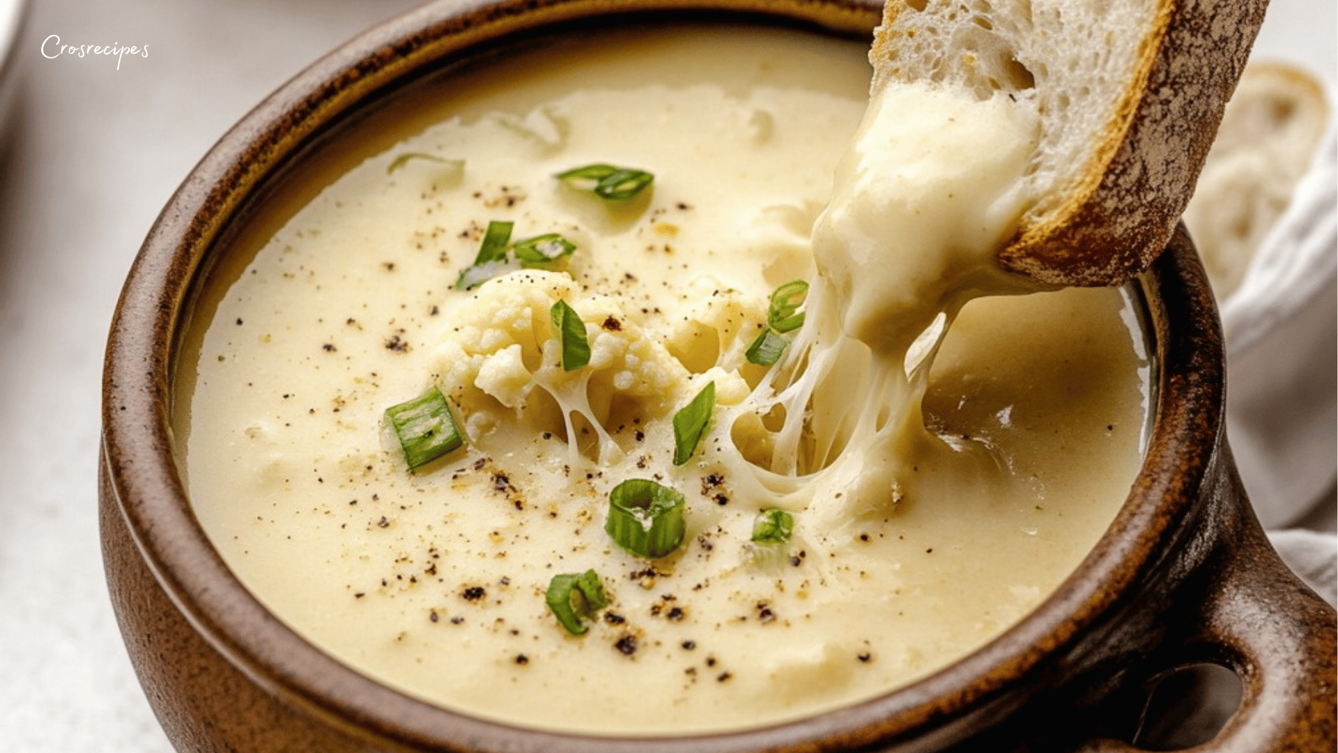 Bol de soupe de chou-fleur rôti au cheddar et à l'ail avec des croûtons dorés.