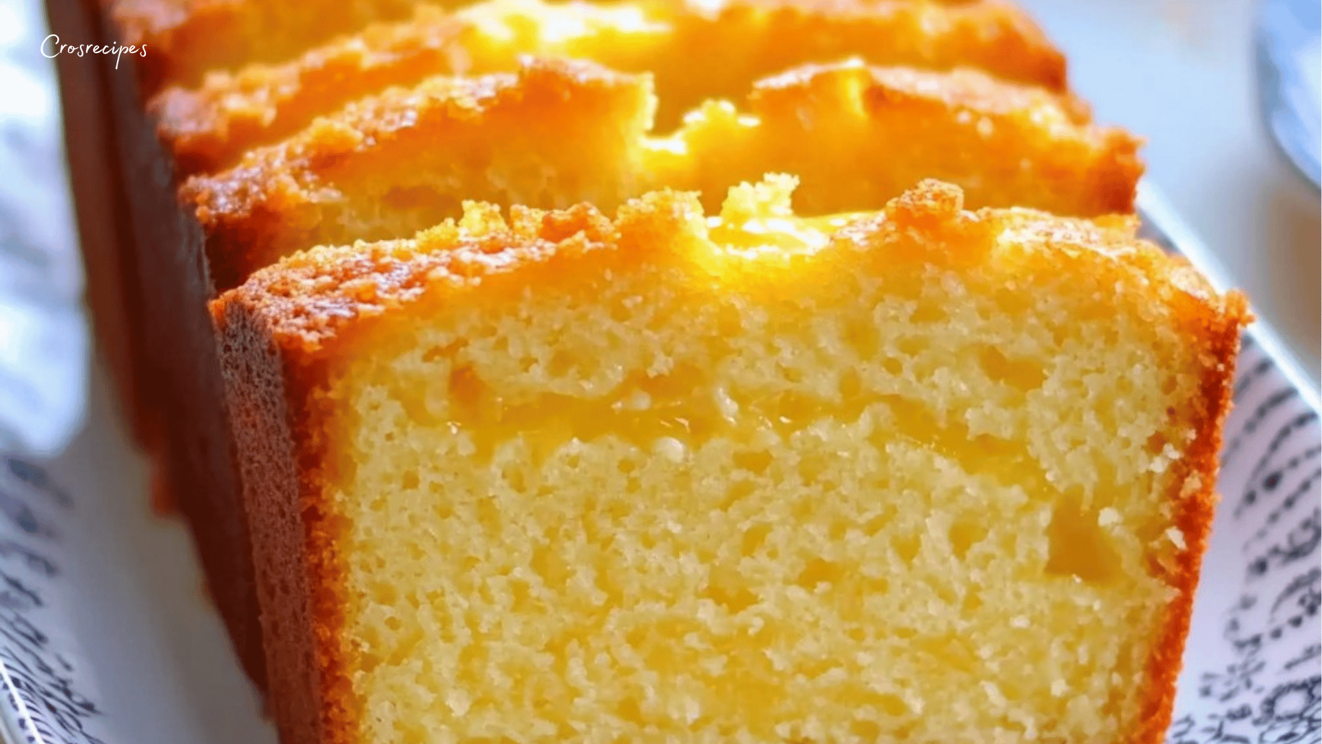 Cake citron moelleux nappé d'un glaçage au citron, posé sur une assiette avec des tranches de citron.