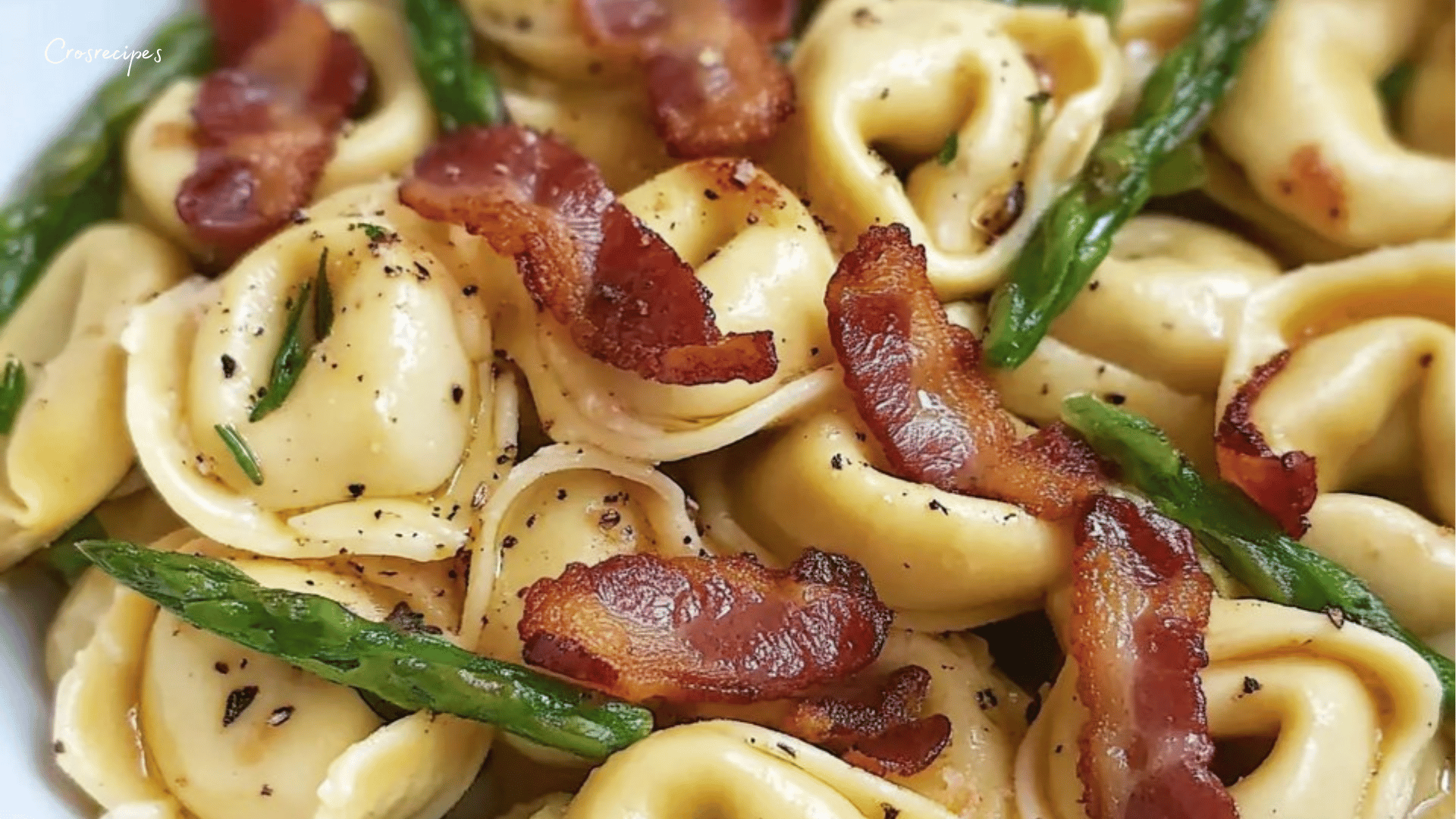 Assiette de tortellini avec asperges, bacon croustillant et beurre noisette, garnie de parmesan râpé et de feuilles de basilic frais.