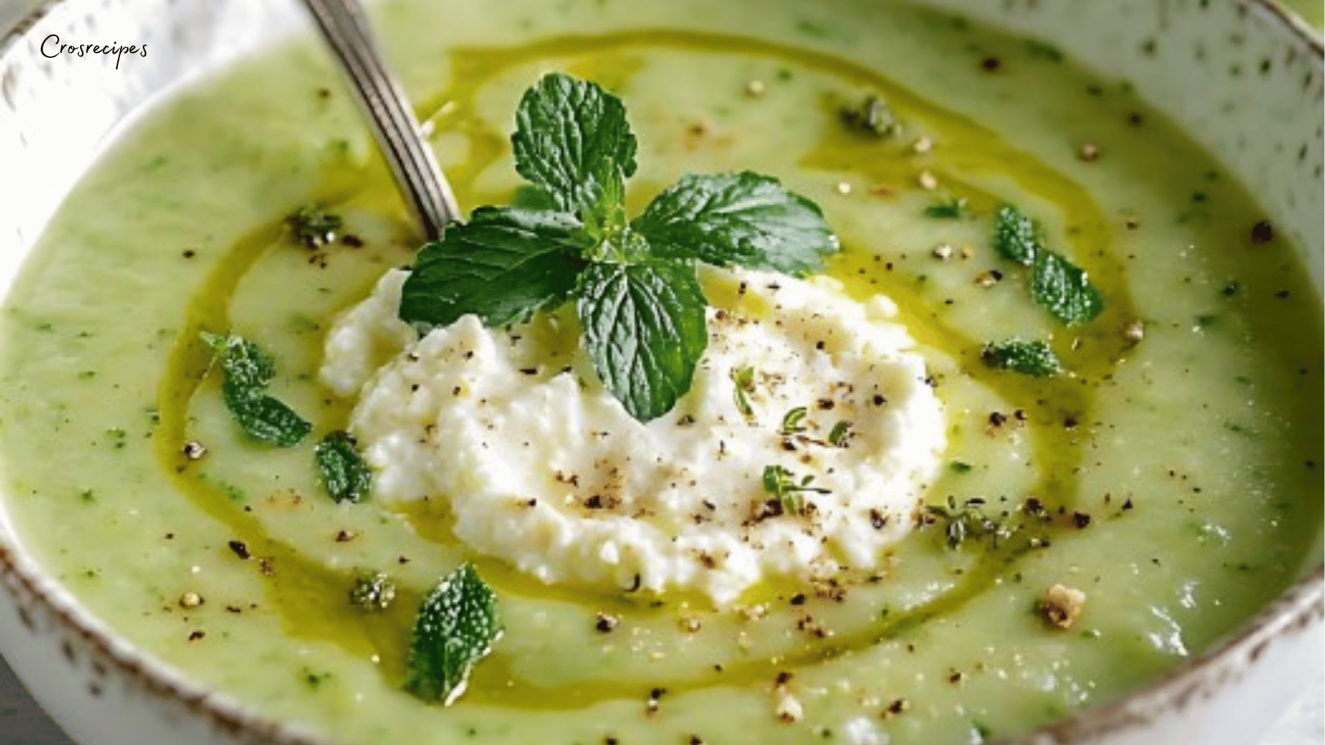 Velouté de courgettes crémeux à la menthe servi dans un bol avec feuilles de menthe fraîche.