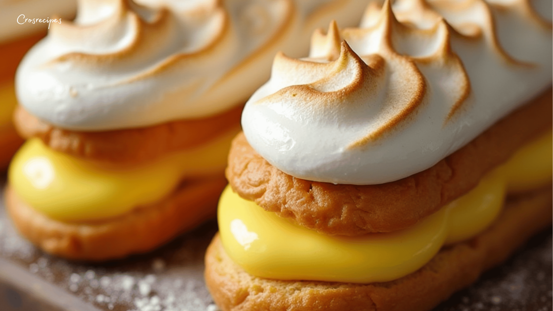 Éclairs au citron meringué décorés avec une meringue dorée et zestes de citron vert.