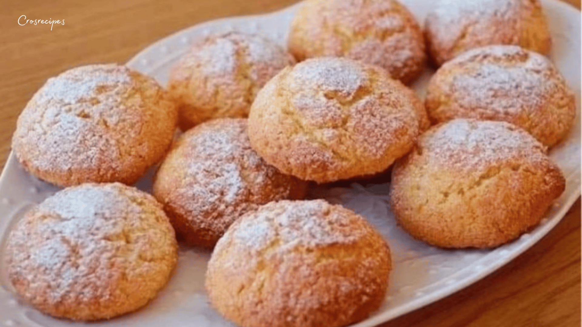 Biscuits à la noix de coco dorés, saupoudrés de sucre glace, sur une assiette.