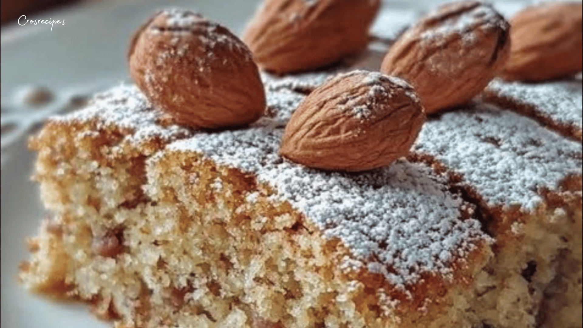 Gâteau aux noisettes moelleux, saupoudré de sucre glace, servi sur une assiette.