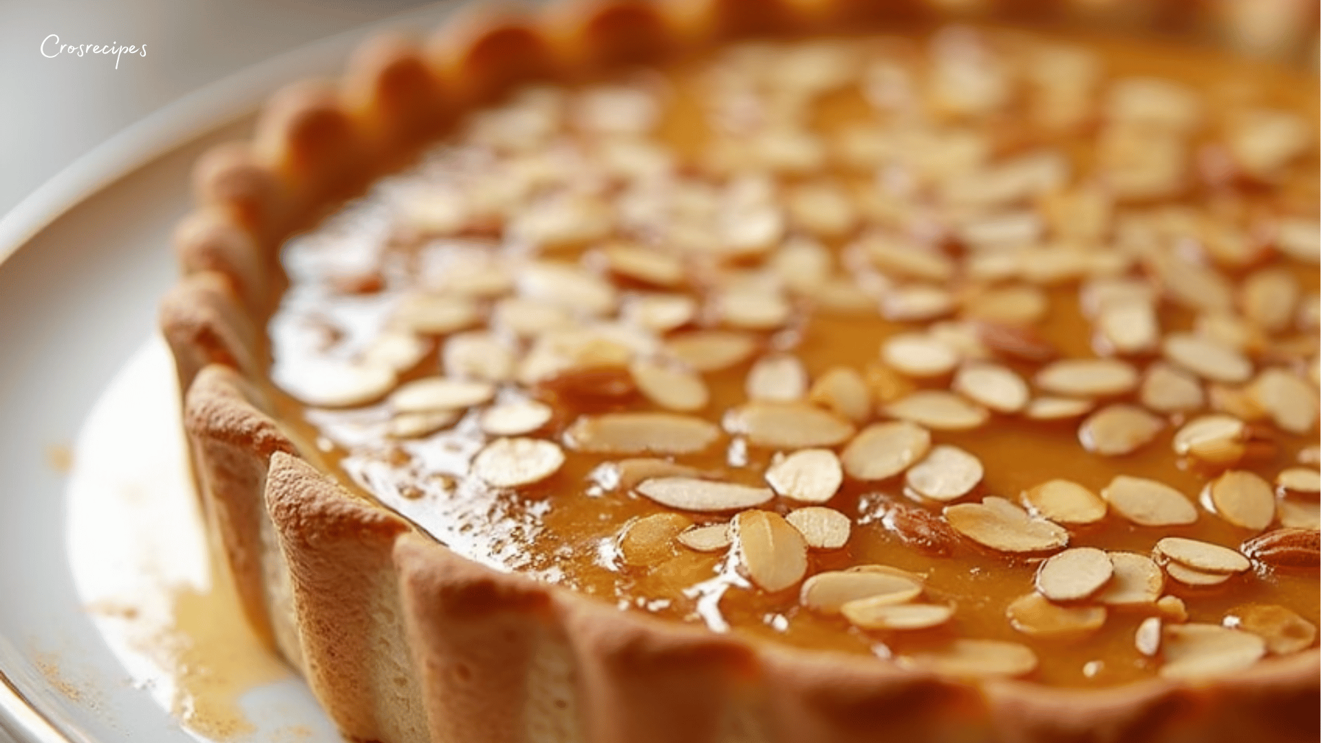 Tarte miel amandes dorée, garnie de lamelles d'amandes effilées, prête à être dégustée.