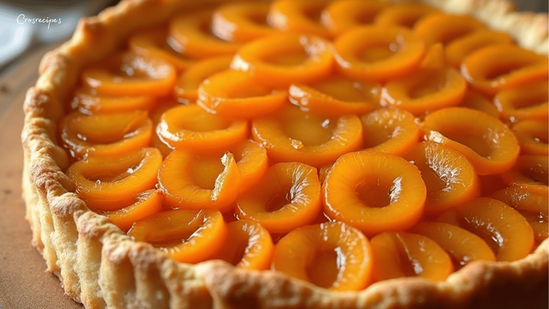 Une tarte à l’abricot dorée, décorée de moitiés d'abricots juteux et saupoudrée de sucre glace.