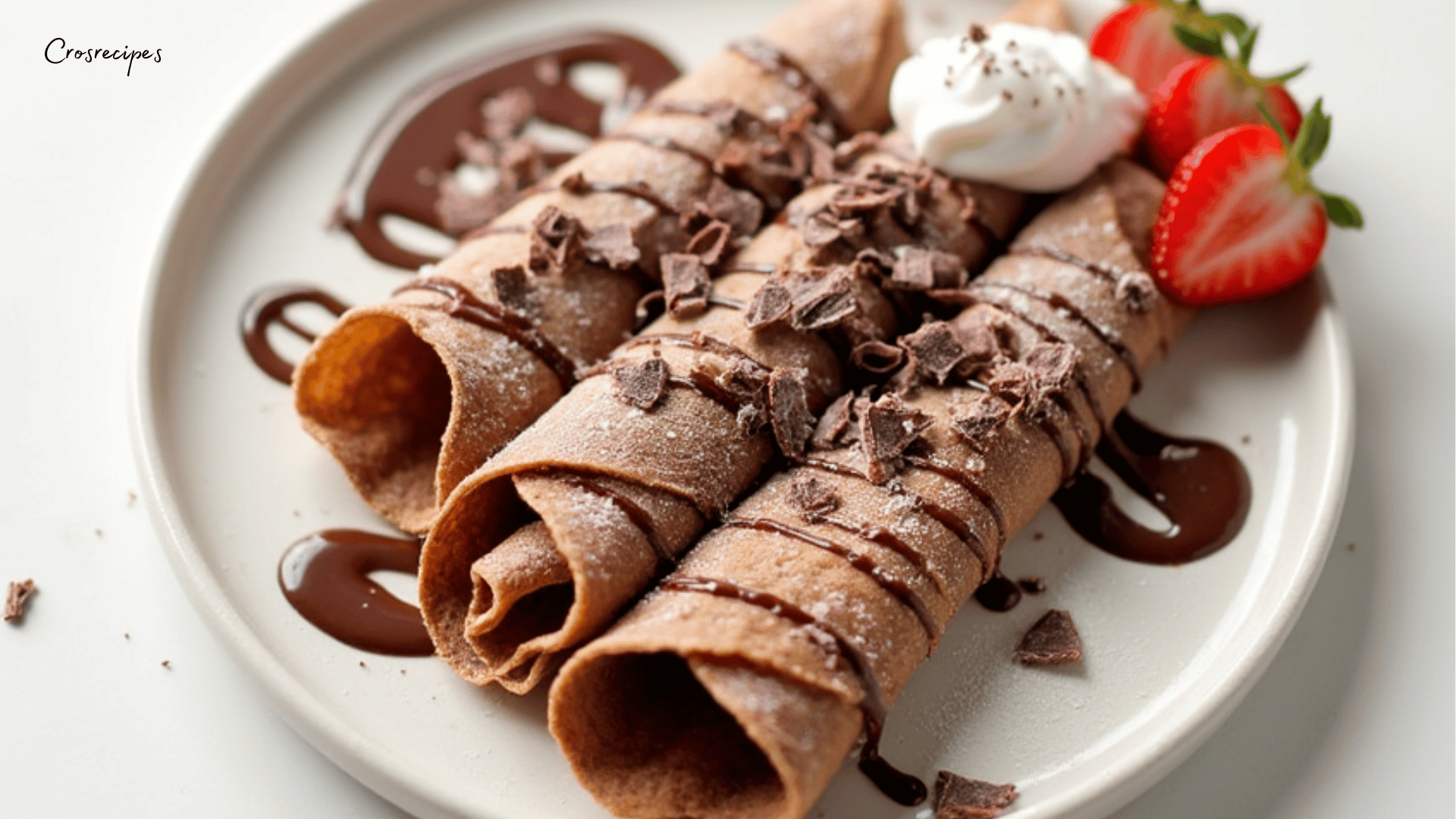 Une pile de crêpes au chocolat garnies de fraises fraîches, de crème chantilly et d'un filet de chocolat fondu.