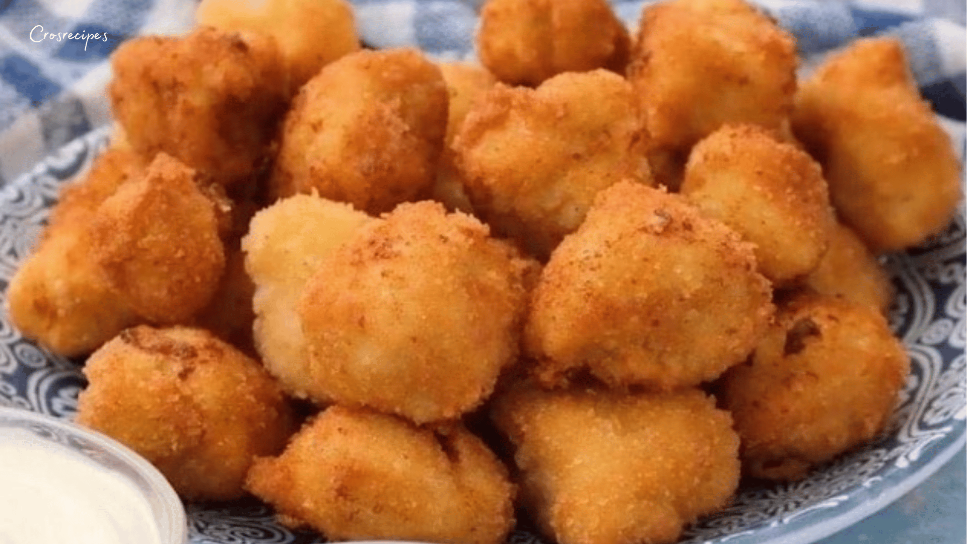 Boulettes de poulet dorées et croustillantes, garnies de persil, servies dans une assiette élégante avec une sauce d’accompagnement.