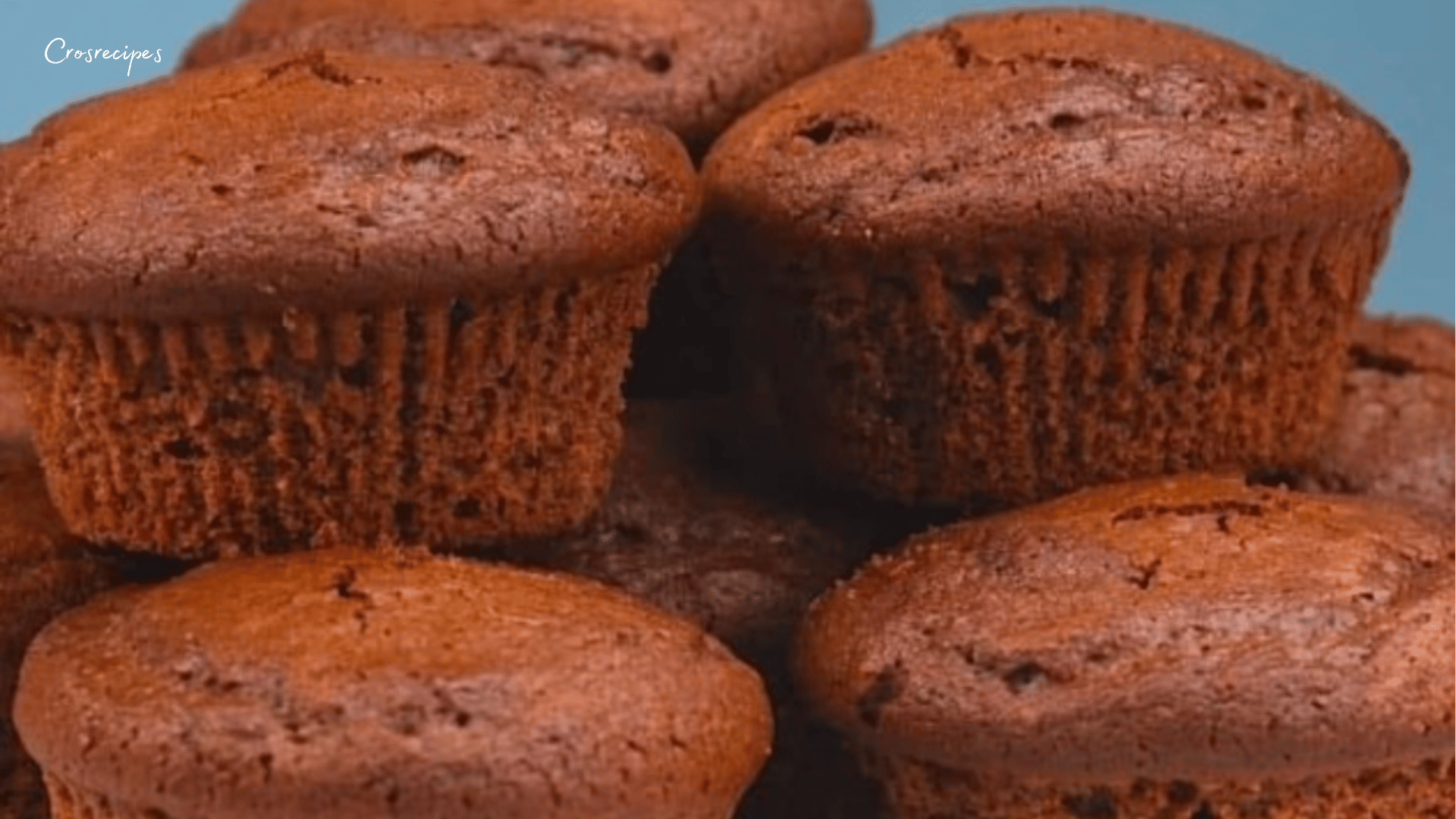 Muffins au chocolat bien gonflés, avec un cœur fondant au chocolat blanc, présentés dans des moules colorés sur une assiette.