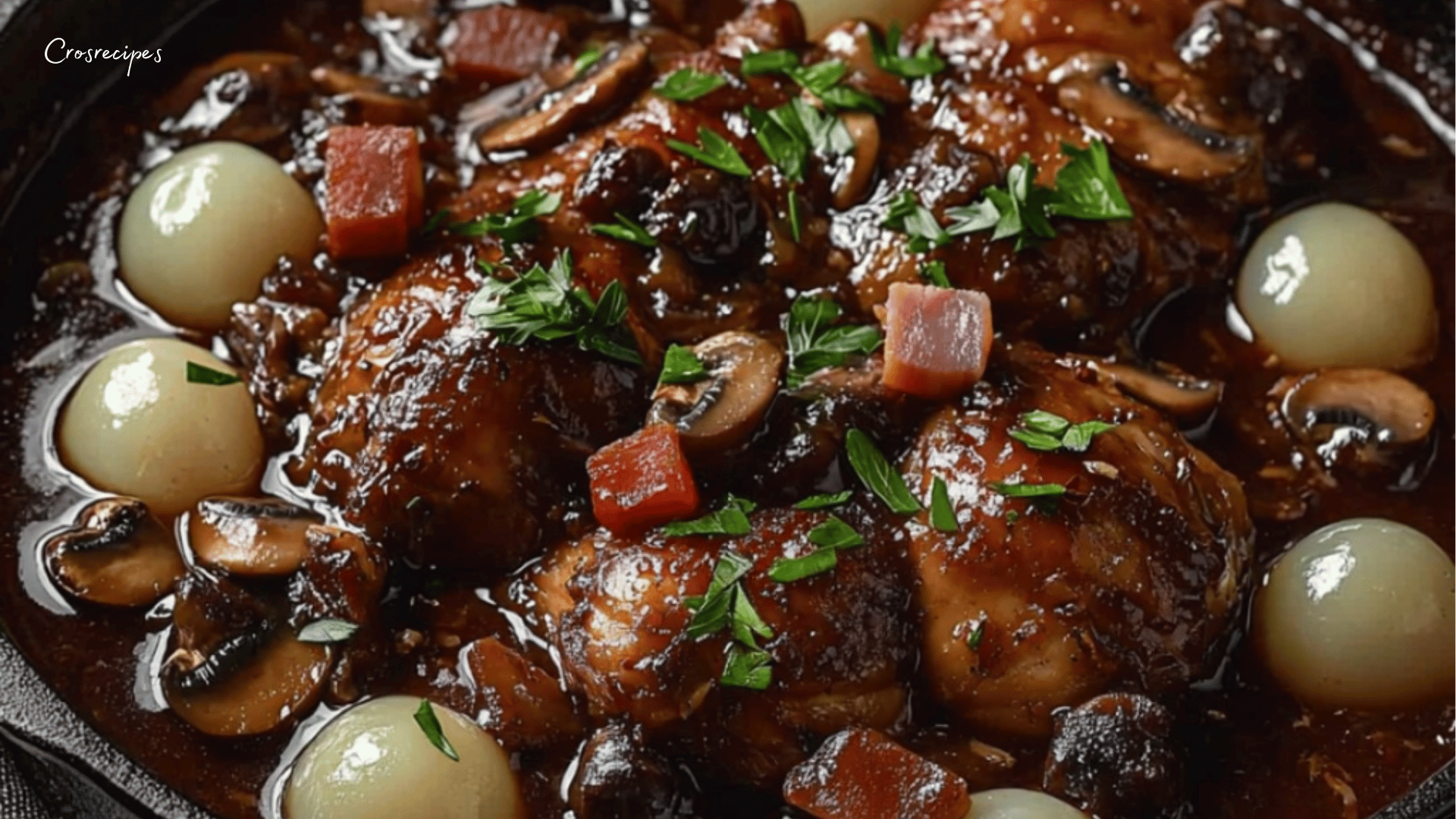 Poulet au vin rouge avec carottes, champignons et oignons grelots dans une cocotte, garni de persil frais.