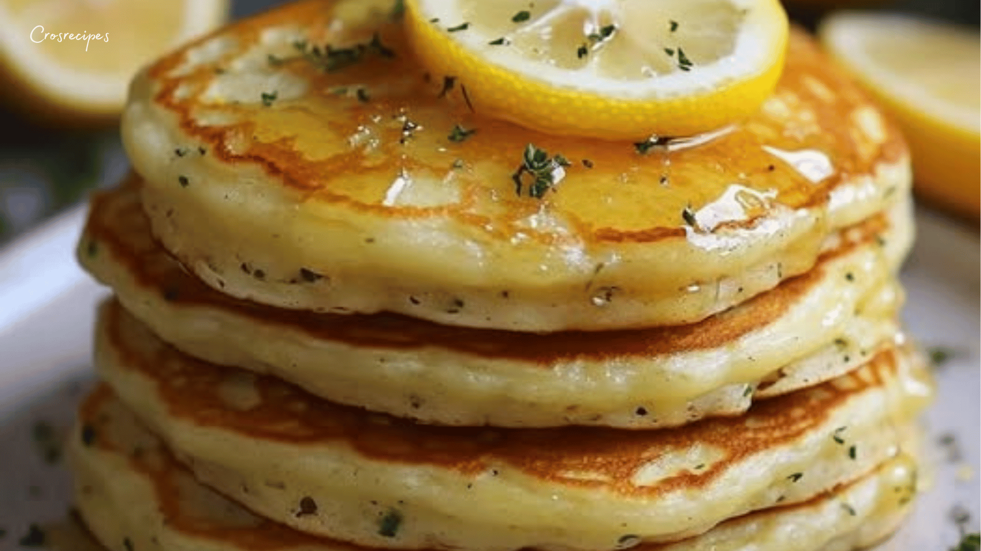 Pancakes dorés au citron et herbes fraîches, garnis de tranches de citron et de sirop d’érable.