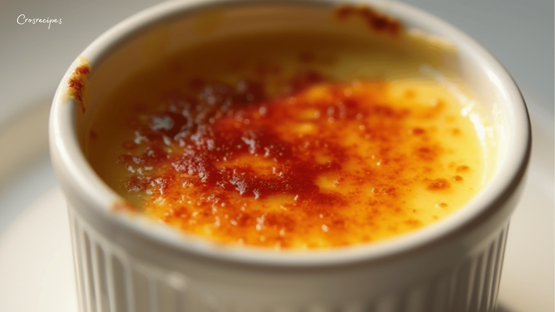 Crème brûlée maison servie dans un ramequin, avec une couche de caramel doré et craquant, accompagnée de fruits rouges.