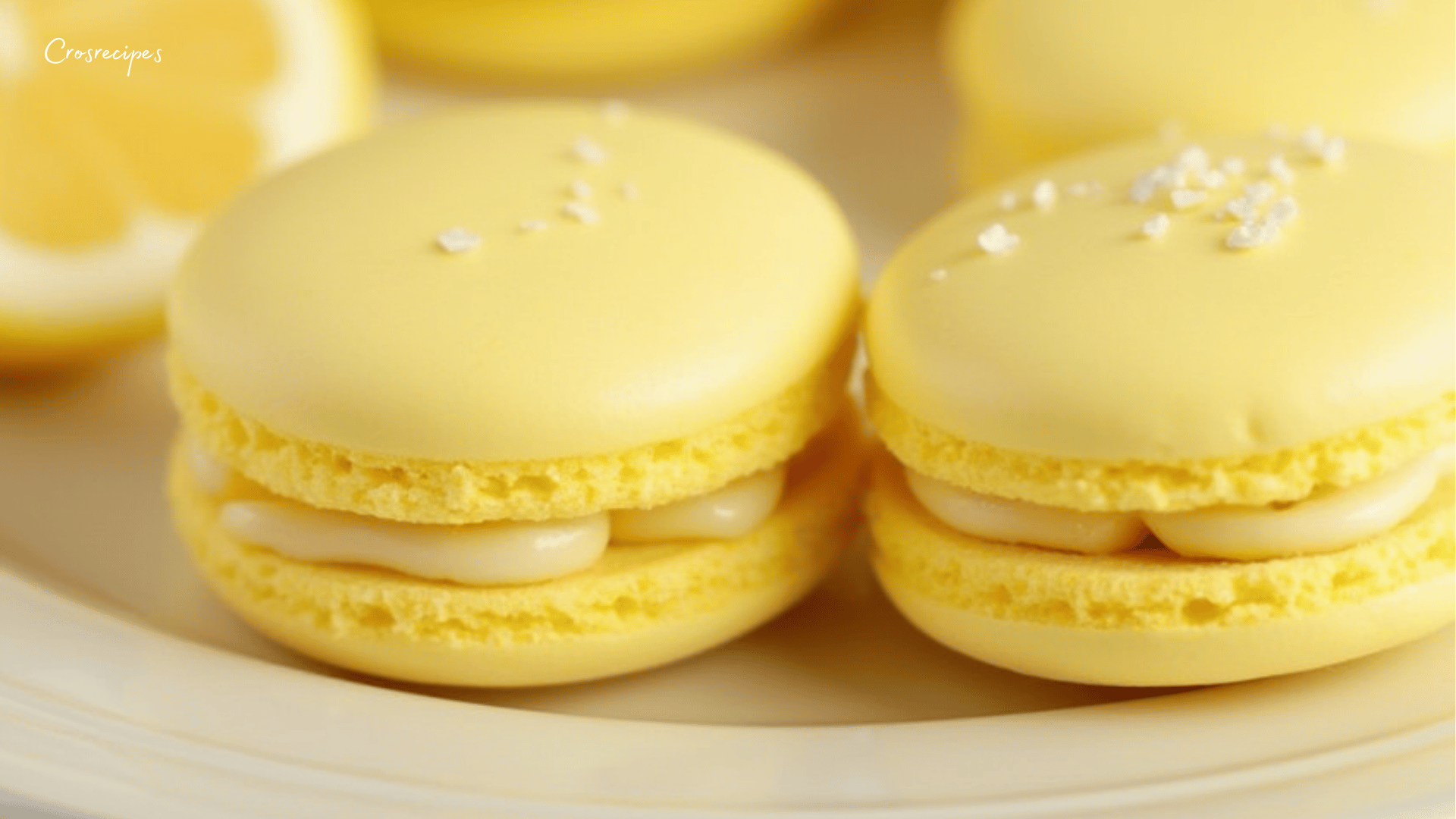 Macarons au citron faits maison avec une coque dorée et brillante, garnis d’une ganache onctueuse au citron, disposés sur une assiette élégante.