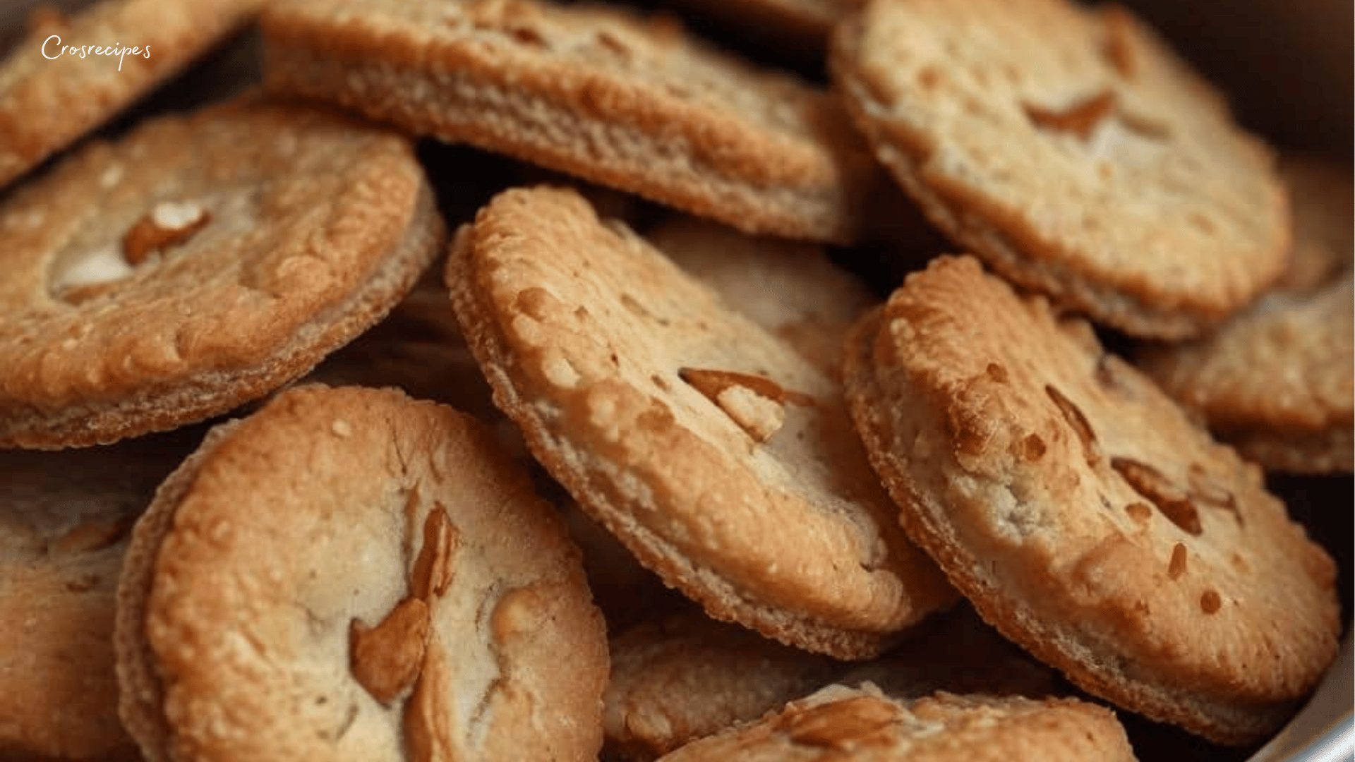 Sablés aux amandes dorés et croustillants, joliment disposés sur une assiette, avec une amande entière au centre pour une touche décorative.