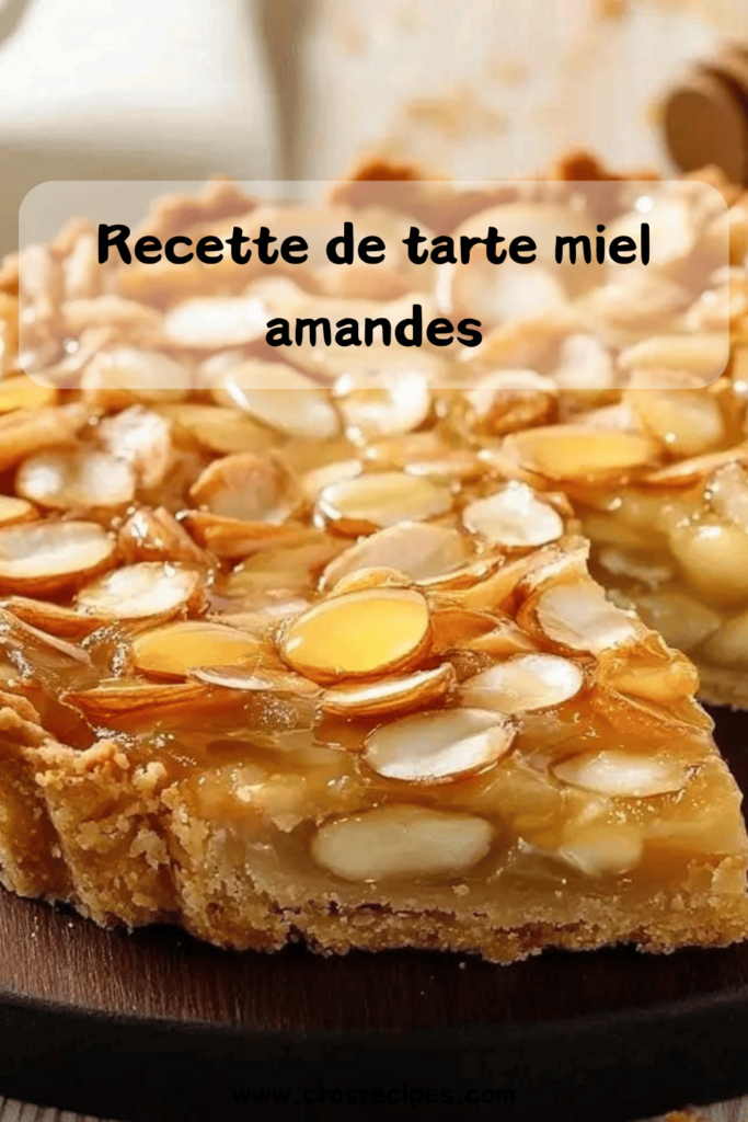 Tarte dorée aux amandes effilées et au miel, avec une pâte sablée croustillante, servie sur une assiette en bois.