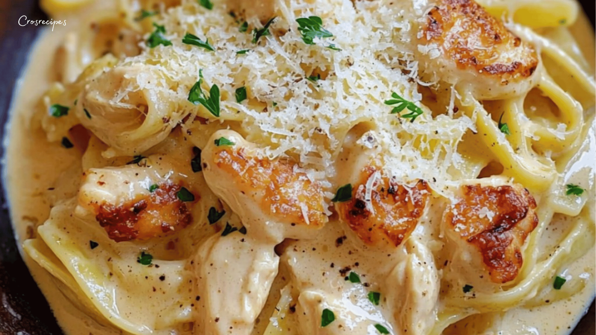 Un plat de pâtes crémeuses au poulet avec une sauce Boursin ail et fines herbes, servi dans une assiette avec du persil frais et du parmesan râpé.