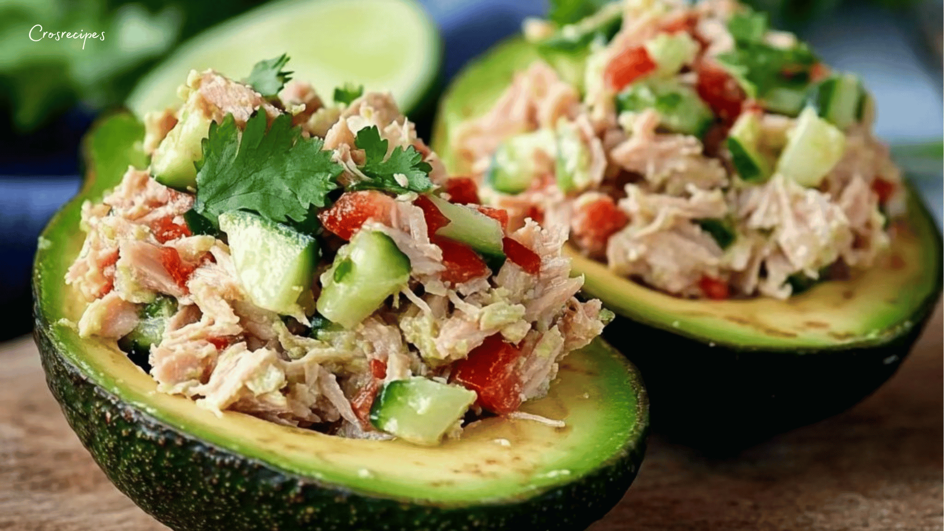 Avocats farcis au thon croquant au citron, garnis de dés de concombre et de poivron rouge, servis frais sur une assiette.