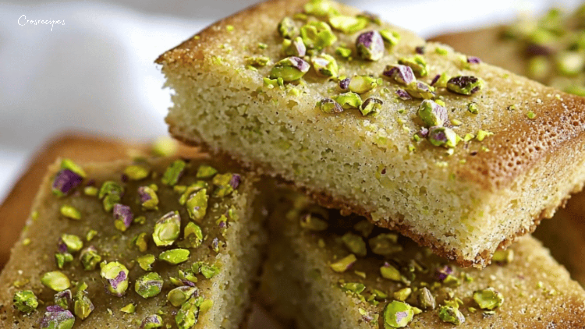 Financiers moelleux à la pistache et au chocolat blanc, parsemés d’éclats de pistaches, servis sur une assiette élégante.
