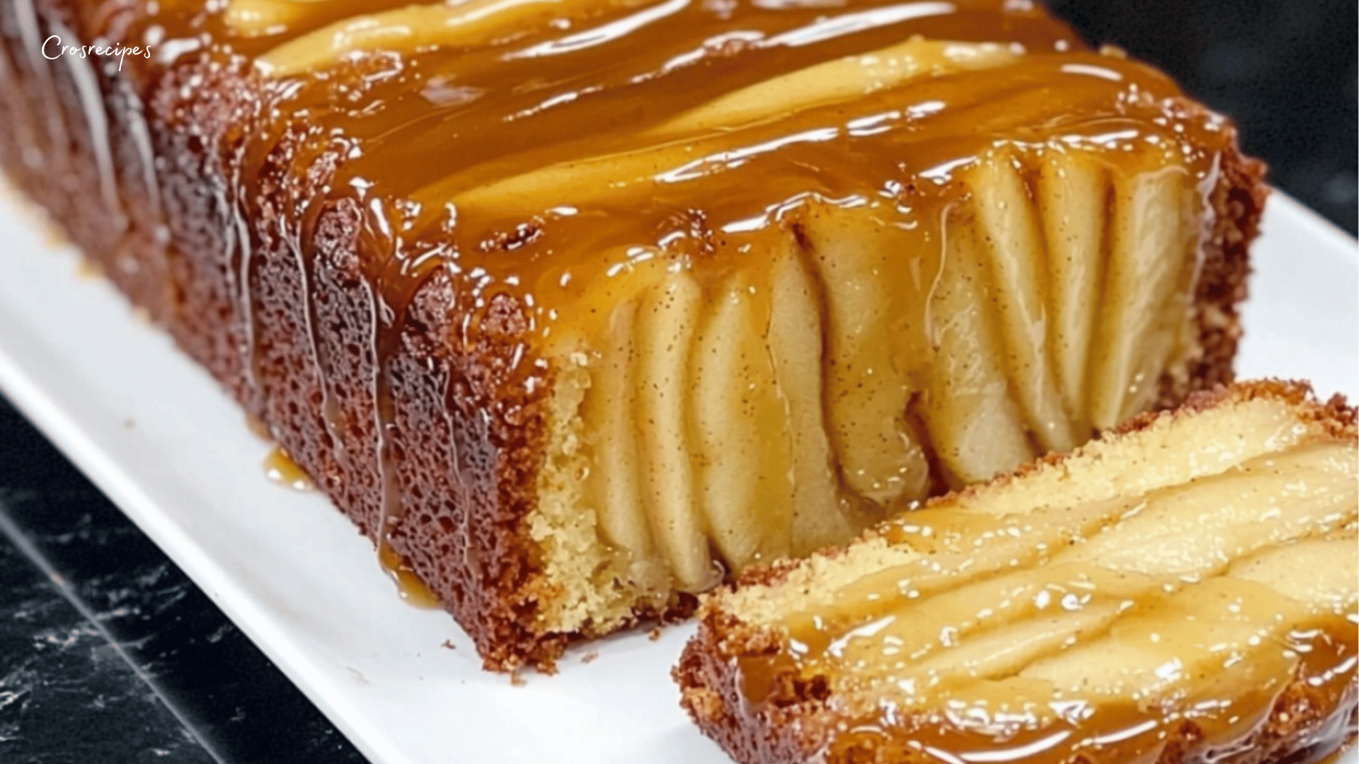 Gâteau moelleux aux pommes et amandes effilées, doré et fondant, servi sur une assiette avec un filet de miel.