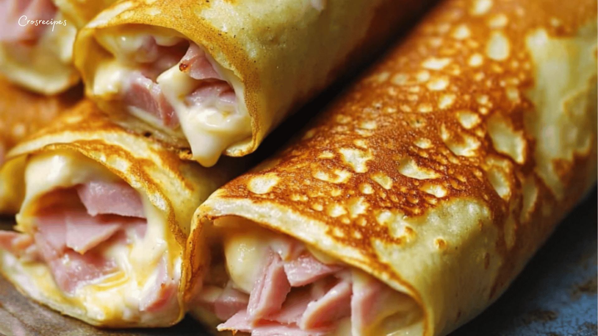 Crêpes dorées au jambon et béchamel fromagère, roulées et croustillantes, servies avec une salade verte.
