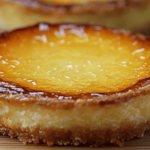 Tartelettes dorées à l’orange, garnies d’une crème onctueuse et surmontées d’une fine couche de caramel brûlé, servies sur une assiette élégante.