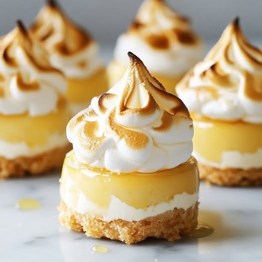 Mini cheesecakes au citron meringué avec une meringue dorée et une base biscuitée croustillante.