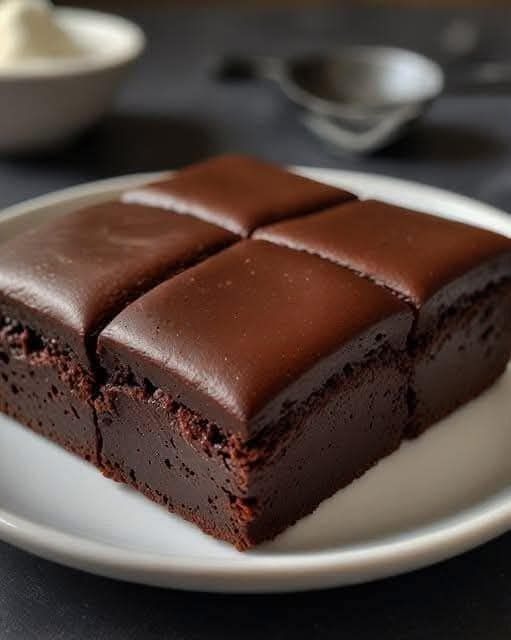 Moelleux au chocolat découpé en parts, avec une texture fondante et une surface légèrement craquelée, posé sur une assiette blanche.