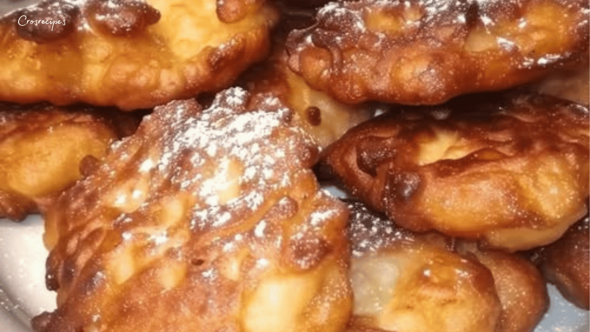 Beignets bretons aux pommes dorés et croustillants, saupoudrés de sucre glace, servis sur une assiette rustique.