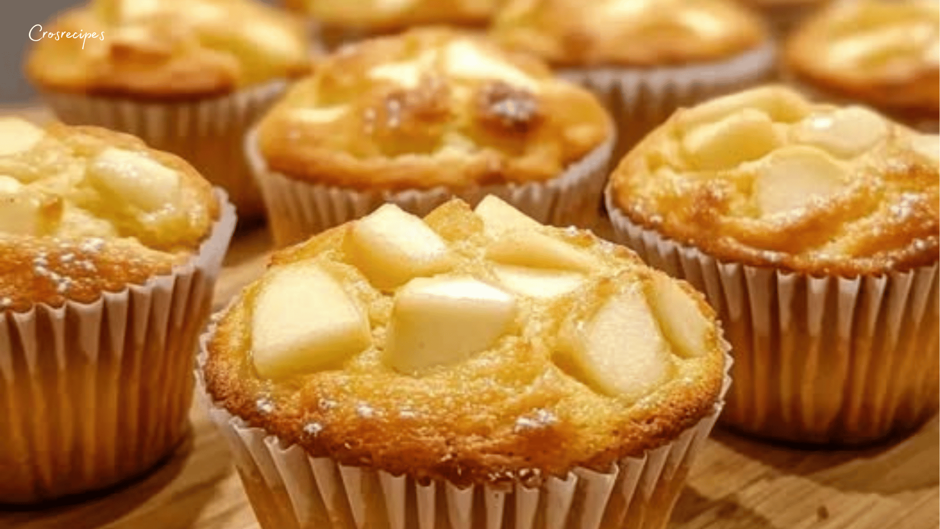 Des muffins fondants aux pommes avec une texture moelleuse, saupoudrés d’une pincée de cannelle, disposés sur une grille de refroidissement.