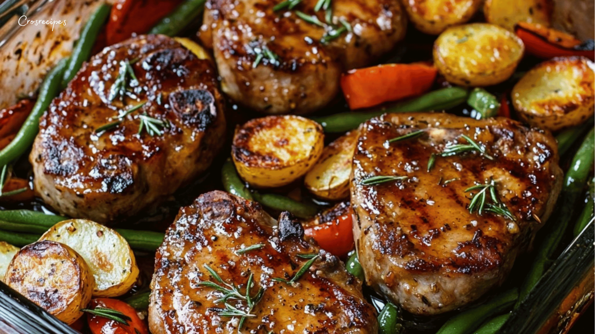 Côtelettes de porc caramélisées au miel et romarin, servies avec des pommes de terre grenailles, haricots verts et poivrons rôtis, garnies de romarin frais.