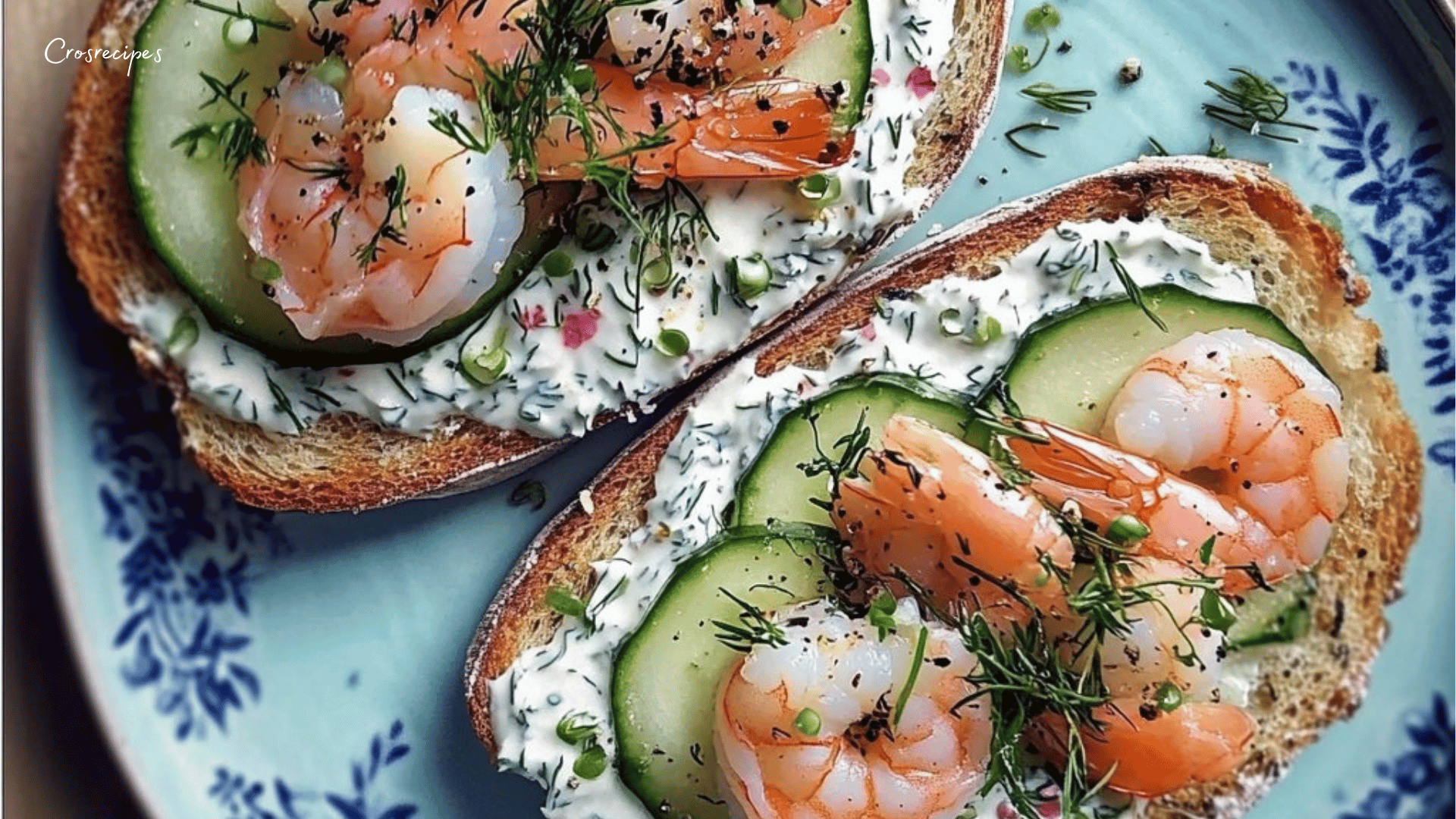 Tartines de pain de campagne garnies de fromage frais, concombres, crevettes et herbes fraîches, servies avec un filet de citron.