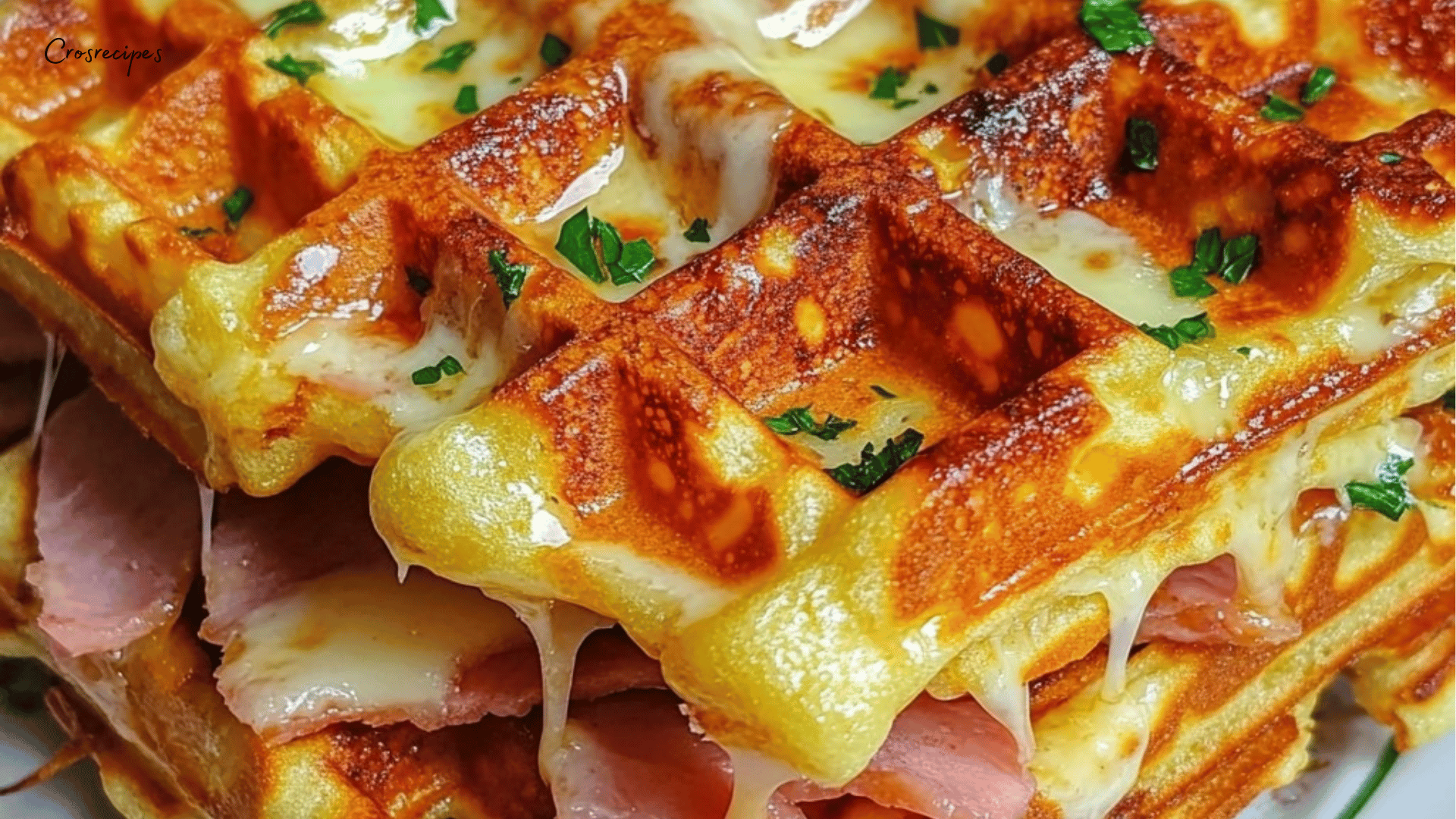 Gaufres dorées garnies de fromage fondu et de jambon, servies sur une assiette avec une salade verte à côté.