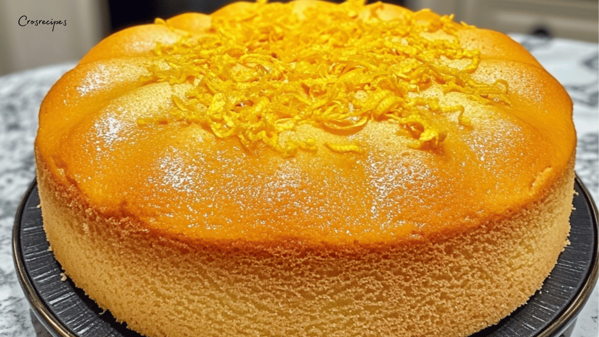 Gâteau moelleux au citron avec glaçage brillant et zestes de citron sur le dessus.