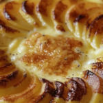 Flan aux pommes doré, garni de fines tranches de pommes et saupoudré de cannelle.