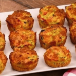 Muffins dorés aux courgettes, fromage et poivron rouge, disposés sur une assiette.