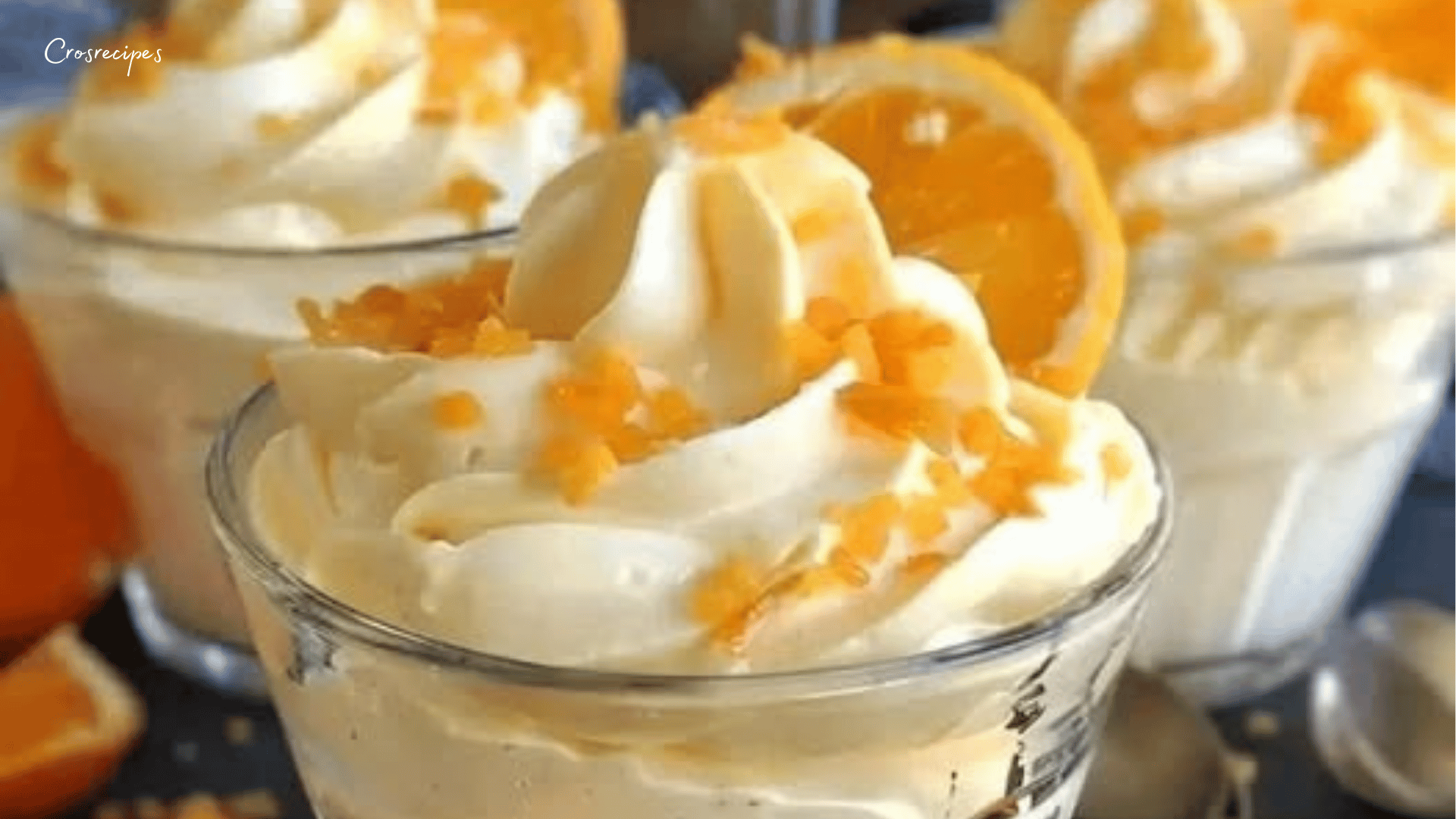 Mousse à la clémentine servie dans une verrine, garnie de zeste de clémentine et d'une légère couche de cacao.