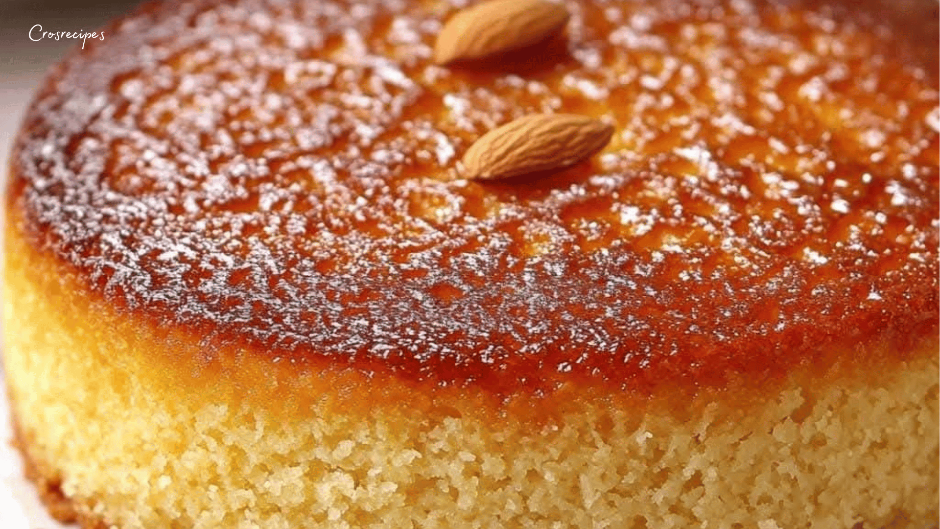 Gâteau moelleux aux amandes et miel doré, saupoudré de sucre glace, avec des amandes effilées grillées sur le dessus.