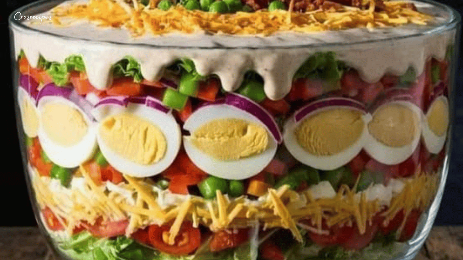 salade à sept étages servie dans un bol transparent avec bacon, œufs, fromage et légumes