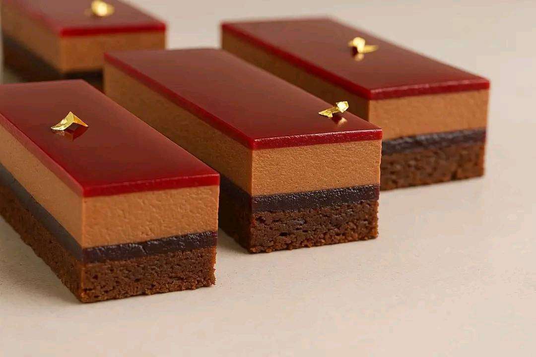 Entremet New York Chocolat Framboise en tranches, superposé de couches nettes, glaçage brillant et framboises fraîches.