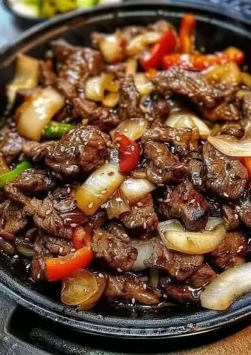 Lamelles de bœuf sautées au wok avec poivrons, oignons et sauce au poivre chinois servies sur du riz jasmin.