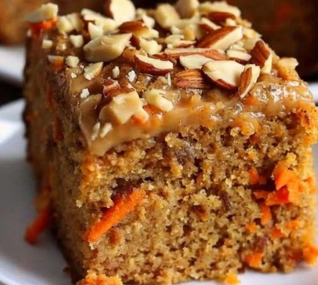 Tranche de gâteau à l’avoine, carottes et pommes, moelleux et doré, avec noix croquantes sur le dessus.