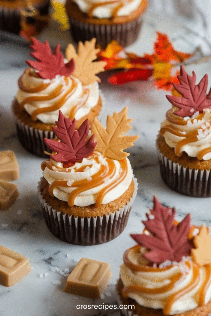 Cupcakes aux épices d’automne décorés de glaçage au caramel au beurre salé et feuilles en fondant, sur fond de table rustique.