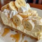 Cheesecake à la crème de banane garni de chantilly, tranches de banane et filet de caramel doré.