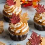 Cupcakes aux épices d’automne décorés de glaçage au caramel au beurre salé et feuilles en fondant, sur fond de table rustique.