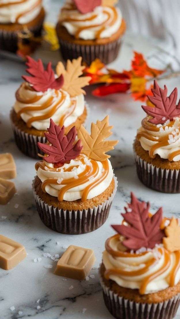 Cupcakes aux épices d’automne décorés de glaçage au caramel au beurre salé et feuilles en fondant, sur fond de table rustique.