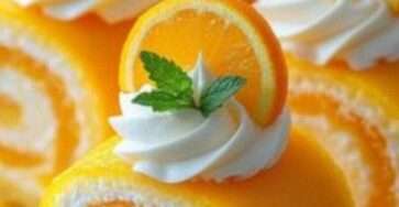 Gâteau roulé moelleux parfumé à l’orange, garni de crème et décoré de tranches d’orange.