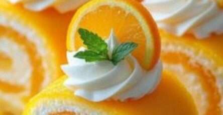 Gâteau roulé moelleux parfumé à l’orange, garni de crème et décoré de tranches d’orange.